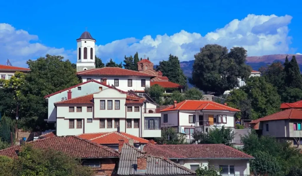 Makedonya Gezi Rehberi için Ohri'nin tarihi bölgesinden, kırmızı çatılı geleneksel evleri ve bir kilise kulesini gösteren fotoğraf.